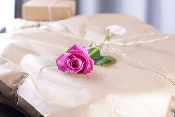 gift in gray wrapping paper and a pink rose