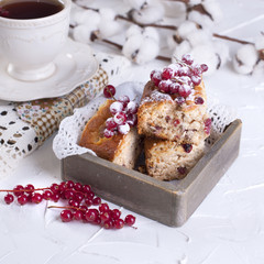 cup of tea and saucer, cupcake with red currant on wooden board and white background, cotton flowers