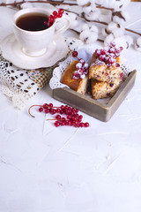 cup of tea and saucer, cupcake with red currant on wooden board and white background, cotton flowers