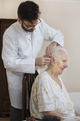 Opieka nad seniorem. Czesanie i układanie włosów. Układanie fryzury u starej kobiety....