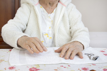 Stara kobieta podaje dłoń podczas zabiegu kosmetycznego.