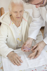 Zabieg pielęgnacyjny dłoni bardzo starej kobiety. Pielęgniarz obcina paznokcie u rąk starej kobiecie.