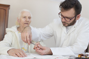 Pielęgniarz obcina paznokcie u rąk starej kobiety. - obrazy, fototapety, plakaty