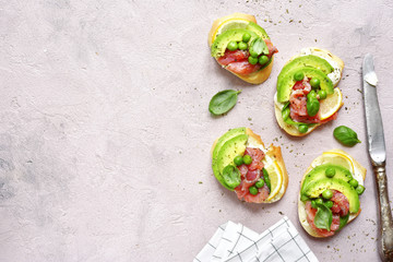 Delicious toasts with salted salmon, avocado, green pea and soft cheese.Top view with copy space.