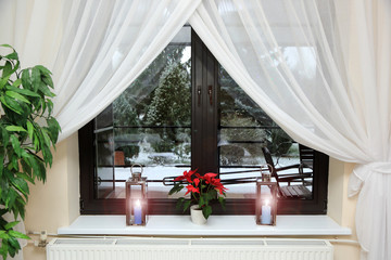Okno w restauracji z czerwonym kwiatek i lampkami na parapecie, Boże Narodzenie. - obrazy, fototapety, plakaty