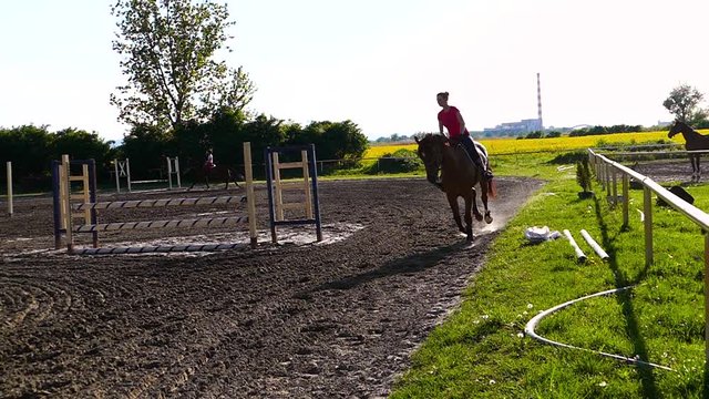 Beautiful happy young girls riding horses on the training ground. Slow motion video. Hi speed camera.