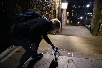 A young man taking photos on the streets of  Edinburgh at night