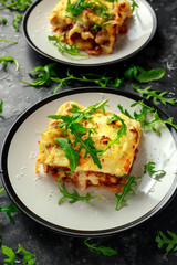 Homemade lasagna with minced beef bolognese and bechamel sauce topped wild arugula, parmesan cheese