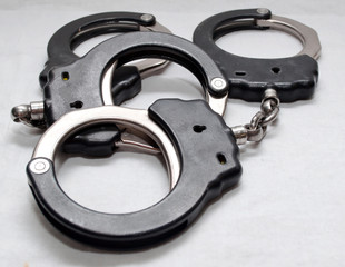 Two pair of handcuffs together on a white background