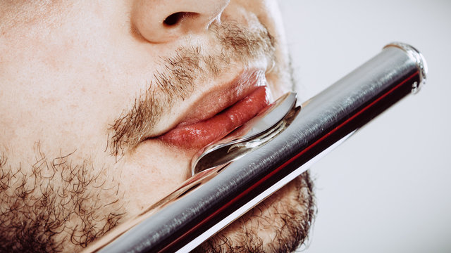Male flutist playing his flute closeup