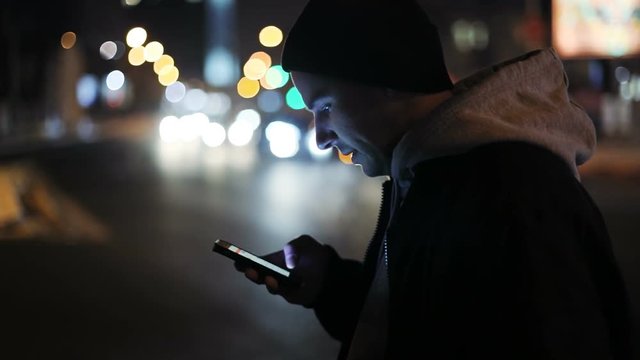 young man holding smart phone street night cars traffic background internet connecting 3g social networking appstore notification touchscreen tap pointing finger chat typing text urban place RED 4K