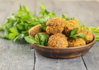 Freshly made falafel on a clay plate on a dark wooden table with tahini sauce.
