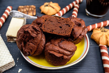muffins on a yellow plate and sweets on a dark wooden background
