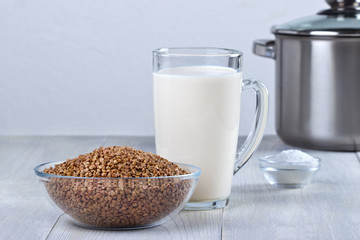 Glass bowl with buckwheat and milk for cooking buckwheat porridge.