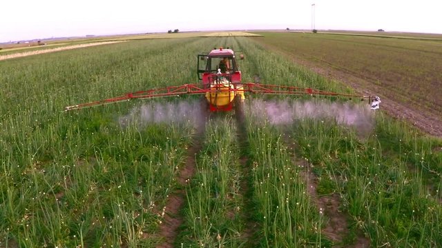 The tractor pulls a machine for spraying onion. Aerial footage.