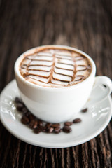 White coffee mug on patterned old wooden floor.