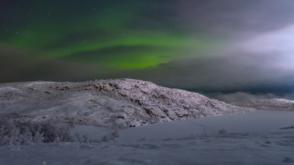 Northern lights ,aurora over the hills and lake ice.