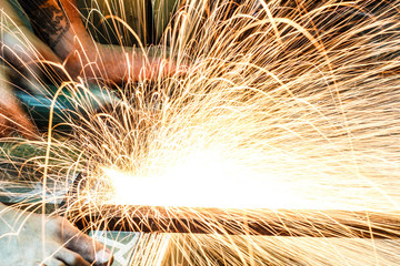  Worker cutting metal with grinder. Sparks while grinding iron
