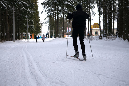 man rides cross-country skiing. Going up the slope with other skiers following.