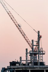 Fototapeta na wymiar cranes on top of under construction high-rise building at twilight
