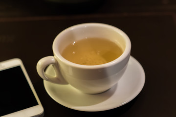 Fototapeta na wymiar cup of green tea nd white phone on table