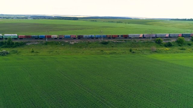 A long freight train moving among green fields. 