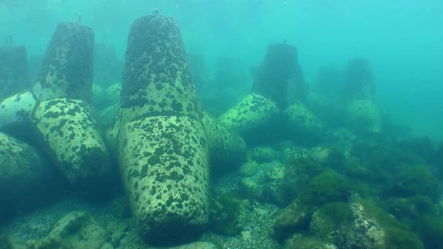 Camera is come near to hydrotechnical protective concrete structures - tetrapods on the seabed.
