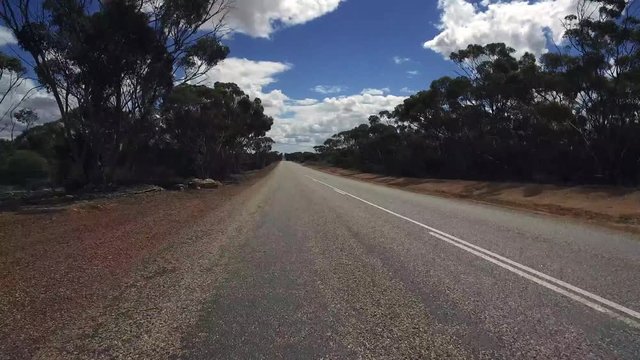 Gerade Fahrstrecke mit teilweise bewölktem Himmel in einem PKW auf einem Highway in West-Australien mit Kamerablickwinkel nach vorne