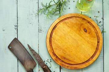 Culinary background. Ancient meat knife above the cutting board, various spices and rosemary. Flat lay, top view with copy space.