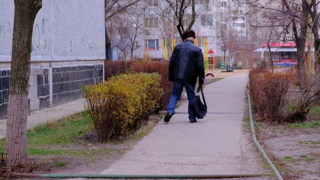 A drunk man staggers, walking along the road in the city, goes unstable gait. 
