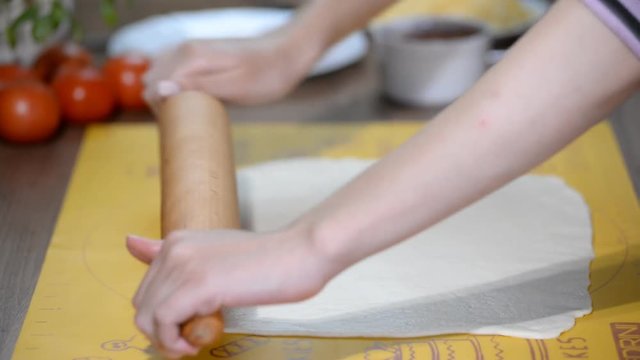 Housewife rolls pizza dough