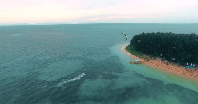 Aerial view of Kitesurfer cruising on empty blue water lagoon on tropical island