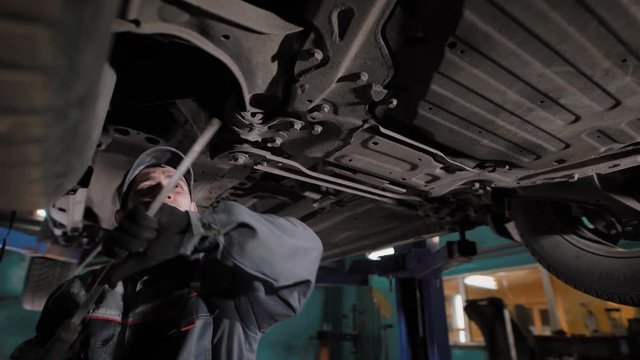 Car mechanic standing under car