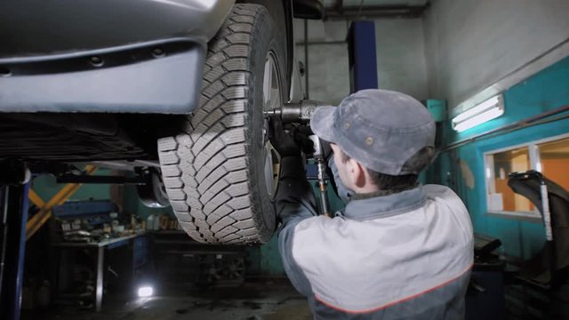 Car mechanic removing wheel from car