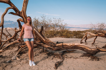 Beautiful girl exploring death valley desert in the middle of dunes during really hot weather.