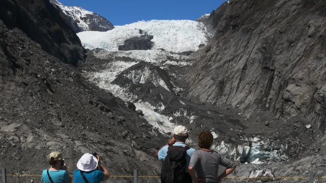 tourists take photographs of franz josef glacier on the weest coast of new zealand