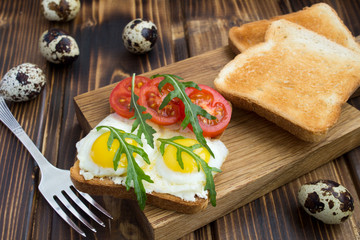 Fototapeta na wymiar Vegetarian sandwich with quail eggs,cherry and arugula on the wooden cutting board