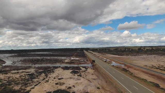 Drohnenaufstieg neben Highway in West-Australien mit Blick auf Steppe und Überschwemmungsgebiet nach Regenzeit