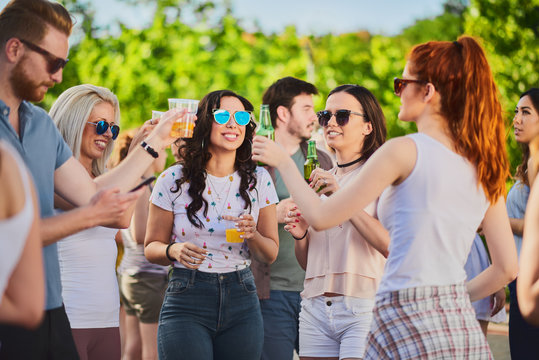 Group of people standing, drinking an having a good time at outdoor party
