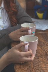Two female teenagers drinking coffee at cafe restaurant with cup of espresso hot cappuccino on dating. Concept of female hands love and coffee. Italian delicious caffeine drink aroma latte