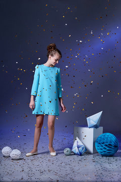 Pretty girl in an elegant blue dress for teenage girls with a make-up. New Year's party.Minimalism and origami.Fashion kid christmas photos.