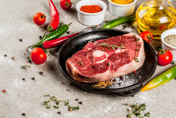 Fresh raw meat. A piece of lamb's tenderloin, with a bone, with a cutting ax, with spices for cooking on grey stone table Copy space