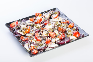 Close up of beetroot salad with fresh tomato, goat cheese, parmesan, pesto