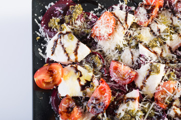Close up of beetroot salad with fresh tomato, goat cheese, parmesan, pesto