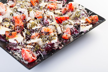 Close up of beetroot salad with fresh tomato, goat cheese, parmesan, pesto