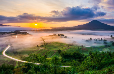 Obraz premium Scenery view of sunrise with mist and traffic trails from Khao Ta-Khian Ngo Viewpoint. Location in Khao Kho District, Phetchabun, Thailand, Southeast Asia.