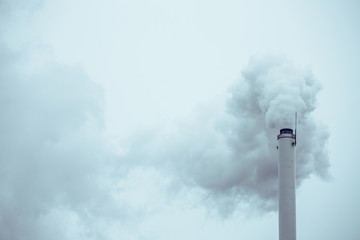 Industrial long white chimney with white smoke going outside. Vintage effect.