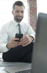 businessman holding a smartphone and looking at the camera