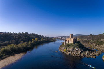 Fototapeta na wymiar Aerial view of the Armourol Castle with a boat passing in the Tagus River in Portugal; Concept for travel in Portugal