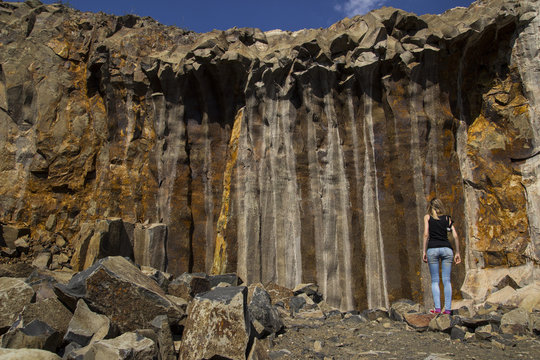 Basalt for building. Basalt career. Basalt pillars. Stone excavation. Heavy industry. A girl examines basalt pillars